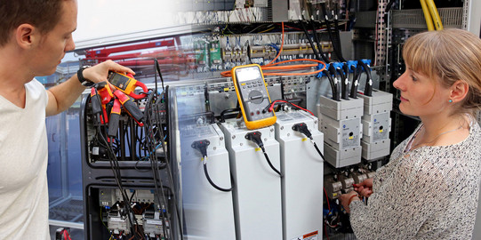 Technisches Equipment in SmartGrid Halle mit Mitarbeiter und Mitarbeiterin Technisches Equipment in SmartGrid Halle mit Mitarbeiter und Mitarbeiterin